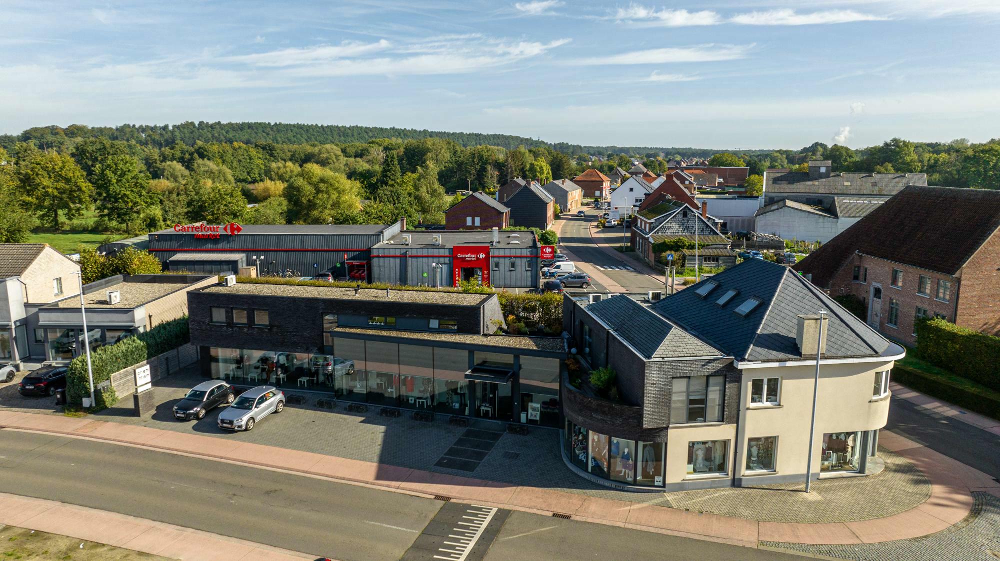 Gunstig gelegen winkelpand(en) met woonst en bovenliggende burelen, voorzien van ruime parking